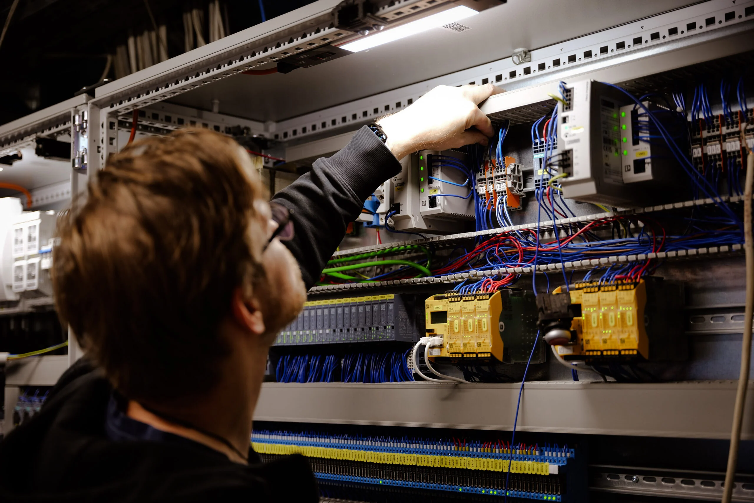 Elektriker bei Servicearbeiten an einem Schaltschrank in einem Gewerbebetrieb
