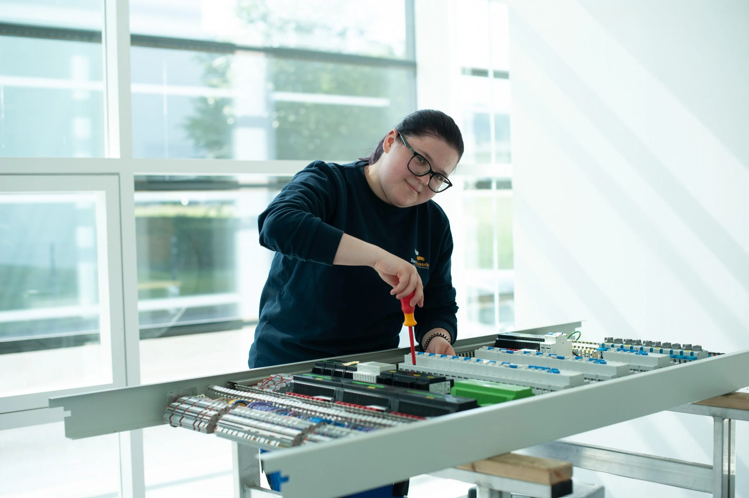 Lehrling des Dorfelektriker arbeitet konzentriert an einem Elektroverteiler