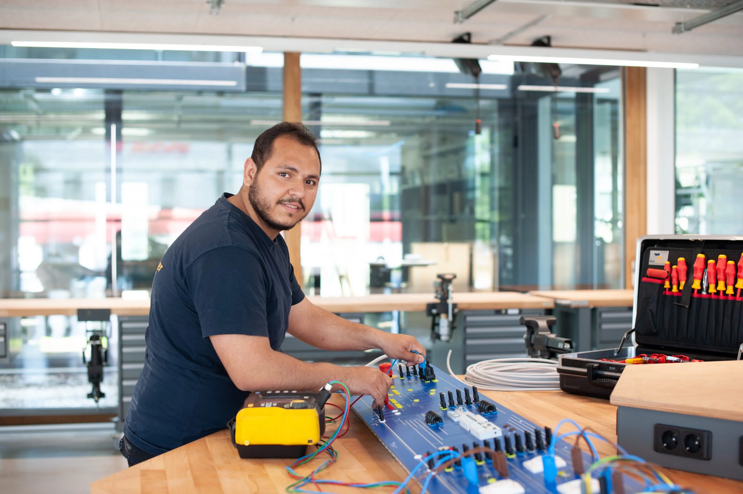 Lehrling mit Werkzeugkoffer, Dorfelektriker in der Lernwerkstatt